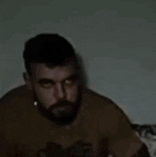 a man with a beard is sitting on a couch with his eyes closed and a necklace around his neck .