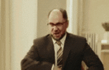 a man in a suit and tie is standing in a room with his arms outstretched .