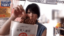 a woman holding a bag of food with chinese writing on it