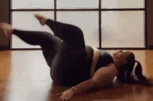 a woman is laying on the floor doing yoga exercises in a gym .