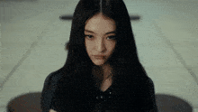 a young woman with long black hair looks at the camera
