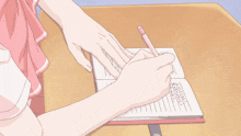 a person writing in a notebook with a pink pen