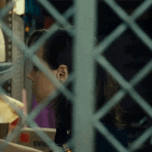 a close up of a woman behind a fence with a sticker on her shirt that says ' a ' on it