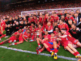 a group of soccer players are posing for a picture with a trophy on the field