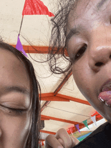 a woman sticking her tongue out next to another woman with a red flag in the background