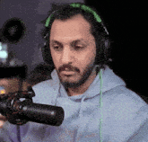 a man wearing headphones is holding a microphone in front of him .