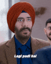 a man wearing a turban and a suit says " lagi padi hai "