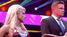 a woman in a wrestling ring is standing next to a man in a suit and tie .