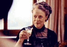 a woman is holding a martini glass in her hand and smiling .