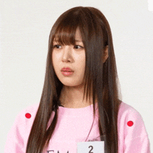 a woman with long hair is wearing a pink shirt with the number 2 on the front