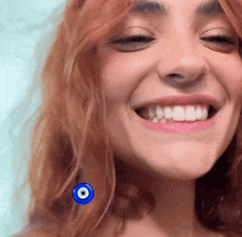 a close up of a woman 's face with a blue evil eye pinned to her hair