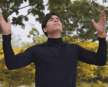 a man with his arms outstretched in front of a tree