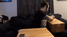 a man sitting on a couch holding a cardboard box that says dyslexia on it