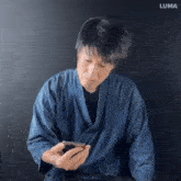 a man in a blue robe is looking at a cell phone .