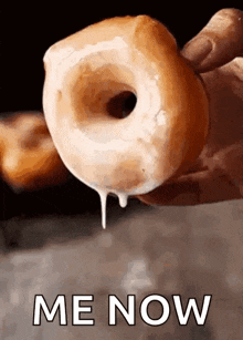 a person is holding a donut with icing dripping out of it and the words me now written below it .