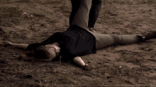 a woman in a black shirt is laying on her back in the dirt