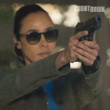 a woman wearing sunglasses is taking a picture of herself with a countdown logo in the background