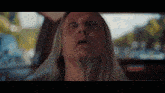 a man with long hair and a beard is sitting in a car with his eyes open