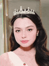 a woman wearing a tiara and earrings has a tomato on her necklace