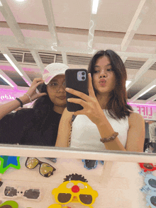 two girls are taking a selfie in front of a mirror with a pink sign that says ' free ' on it