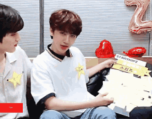 a man sitting next to another man holding a starshipz sign