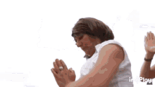 a man and a woman are standing next to each other and the woman is wearing a white tank top .