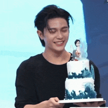 a man is holding a birthday cake with a figurine on top .