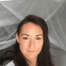 a close up of a woman 's face with a mosquito net in the background .
