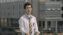 a young man wearing headphones and a tie is sitting on a ledge .