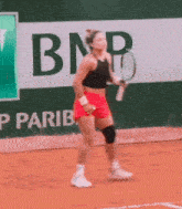 a woman is playing tennis in front of a bnp ad