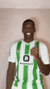a man wearing a green and white striped shirt that says ' howtonil ' on it