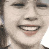 a close up of a woman 's face wearing glasses and headphones and smiling .