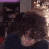 a man with curly hair is making a funny face in front of a computer screen .