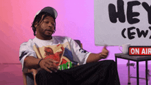a man sits in front of a sign that says " hey crew "