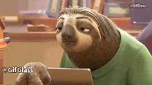 a sloth in a green shirt is looking at a laptop .