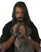 a man with long hair and a beard is hugging a small dog