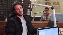 a man wearing headphones is sitting in front of a microphone in front of a sign that says 24 on it