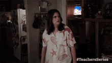 a woman in a shirt with seashells on it is standing in a kitchen .