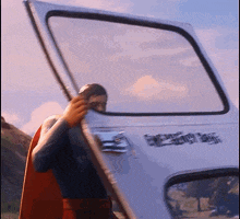 a man in a cape is opening the door of a white van