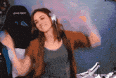 a woman wearing headphones is dancing in front of a black chair that says dxracer