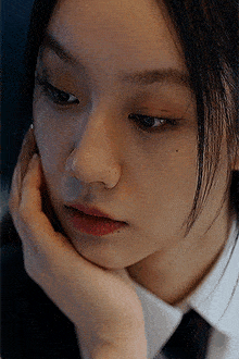 a close up of a woman 's face with her hand on her chin .