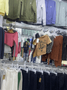 a woman is taking a picture of herself in a clothing store with a t-shirt that says e rush on it