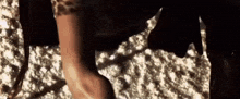 a close up of a woman 's leg in a leopard print dress walking on a dirt road .