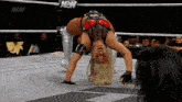 a woman is doing a handstand in a wrestling ring with aew written on the ropes