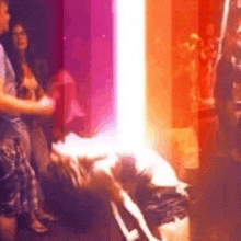 a group of people are standing in a room with a purple light coming out of the corner .