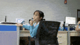 a woman is sitting at a desk with a computer monitor that says ' abc ' on it
