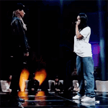 a woman singing into a microphone on a stage with a man standing behind her
