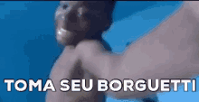 a man without a shirt is swimming in the ocean with the words toma seu borguetti written on the bottom .