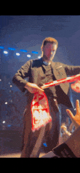 a man in a black suit is holding a bag of popcorn