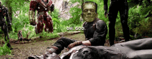 a man with a frankenstein mask on his face is sitting on a fallen soldier